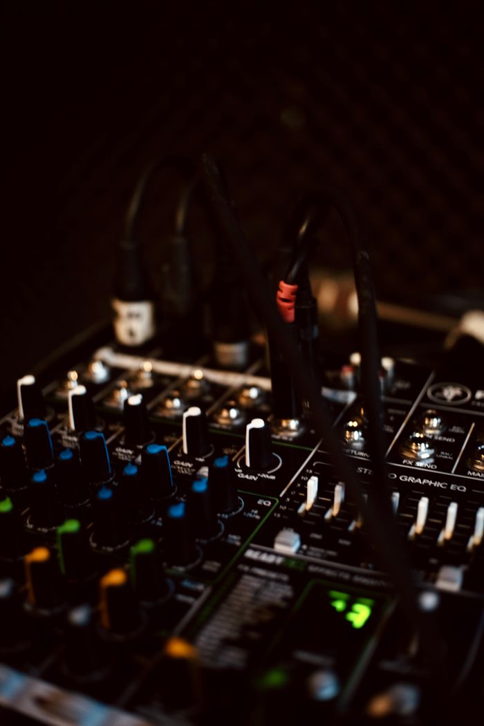A detailed close-up of a dark, professional audio mixing console with various knobs and controls.